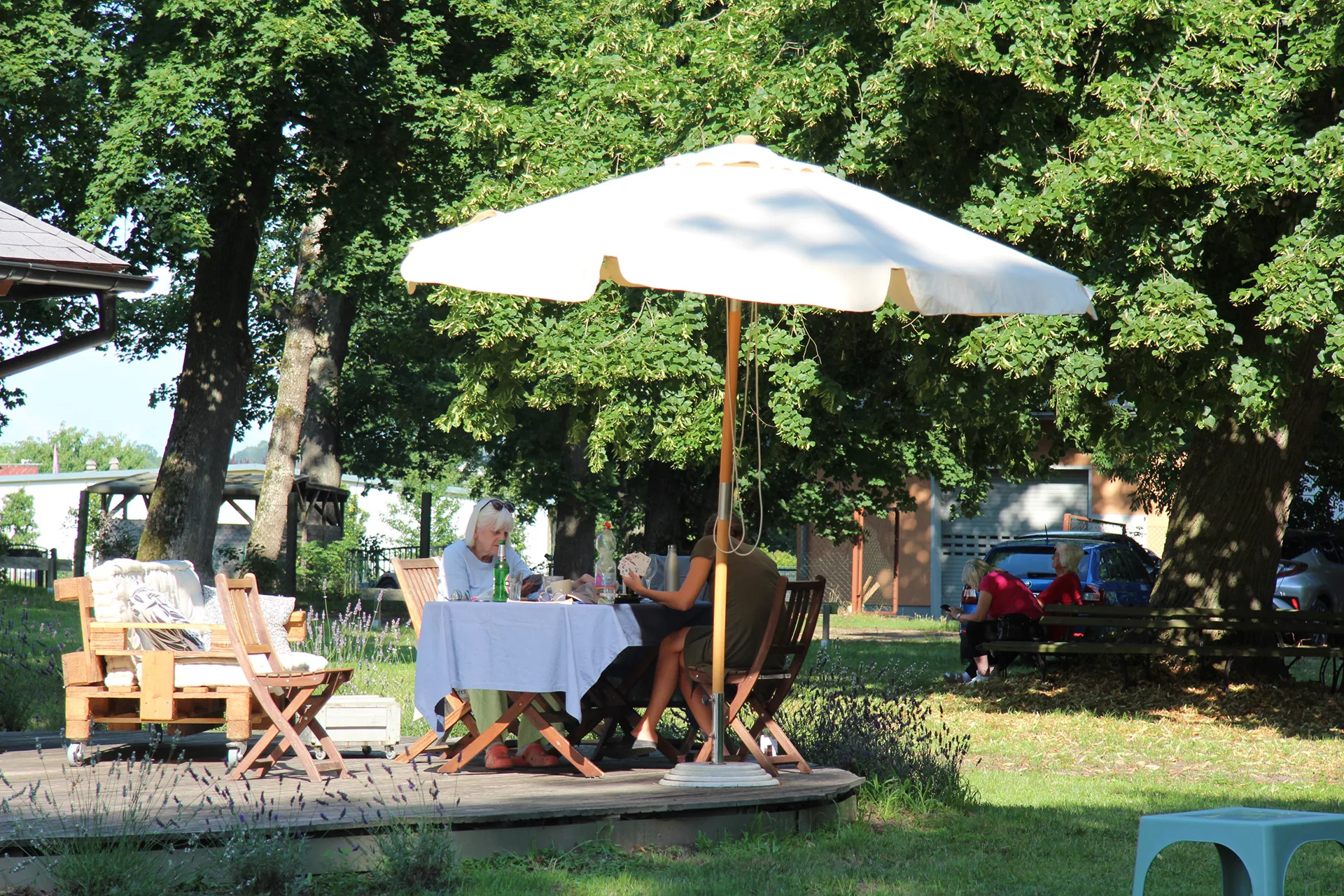 Zwei Frauen sitzen unter einem Sonnenschirm im Garten der Senioren-Wohngemeinschaft